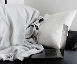 Ein aufgeklapptes Laptop mit Decke und Kissen